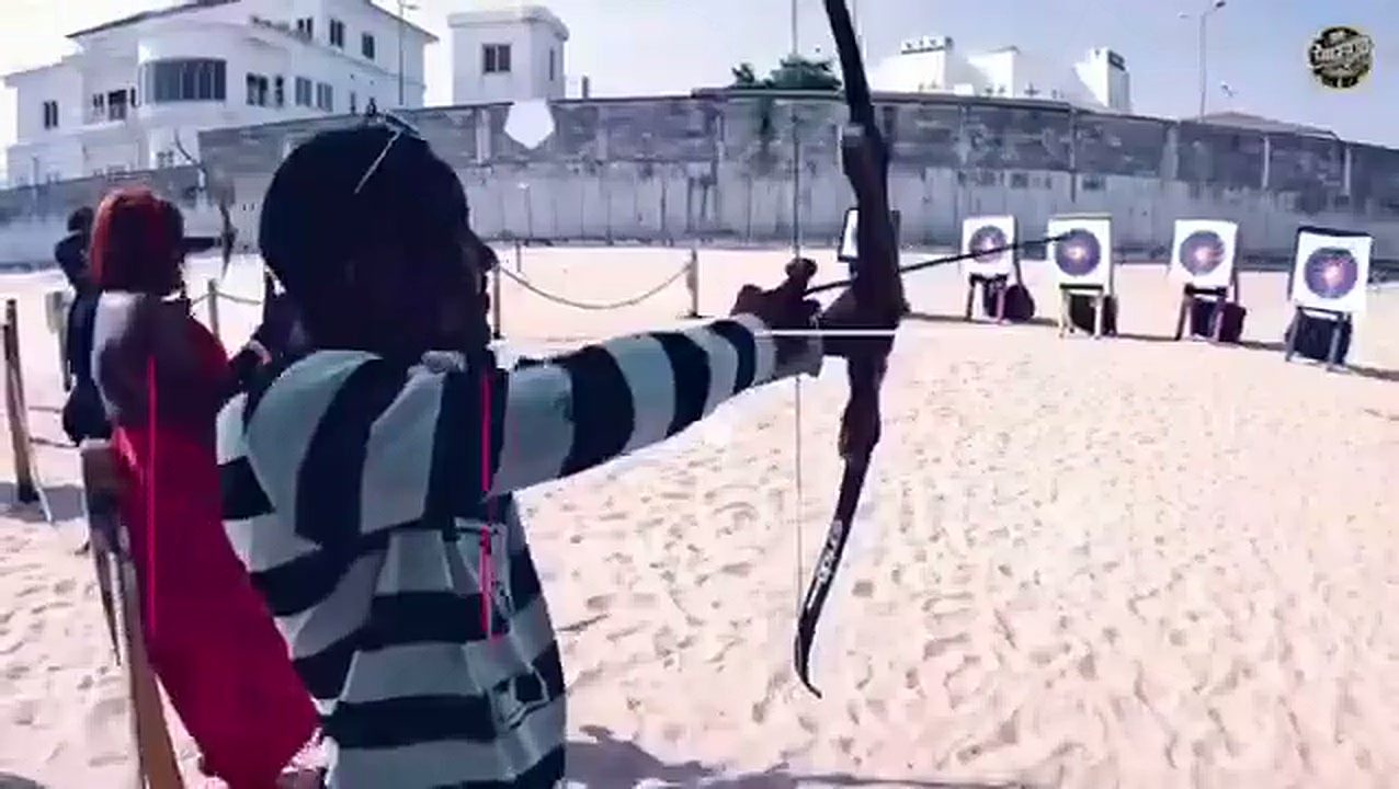 A competitor drawing a bow at a beachfront archery range