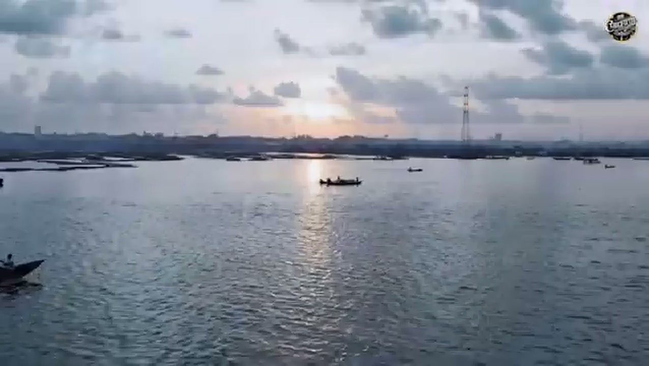 Sun setting over the water with a small boat on the horizon