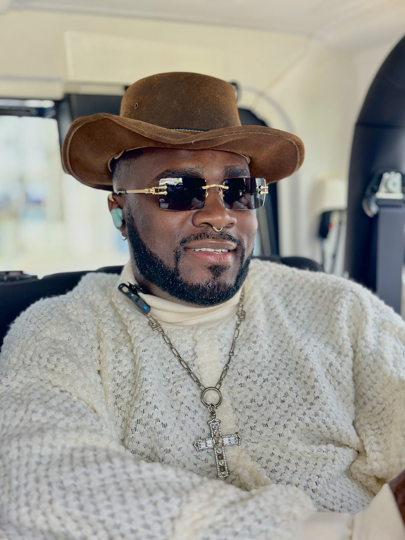 Don Crucifixto in a suede hat and cream knit with a diamond cross